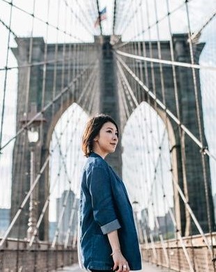 Asian woman standing on a bridge in under a US flag